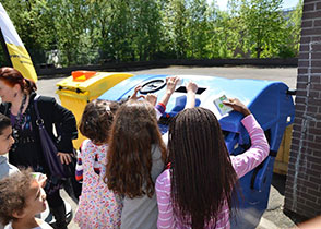 Photo d'enfants jetant des déchets dans un conteneur bleu